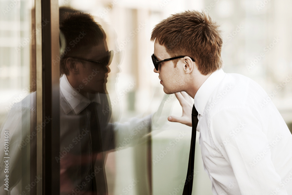 Young businessman looking through a window Young businessman looking through a window
