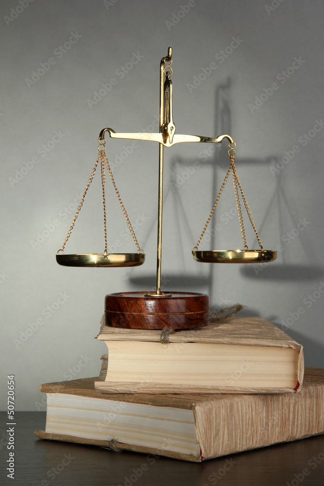 Gold scales of justice and books on grey background Gold scales of justice and books on grey background