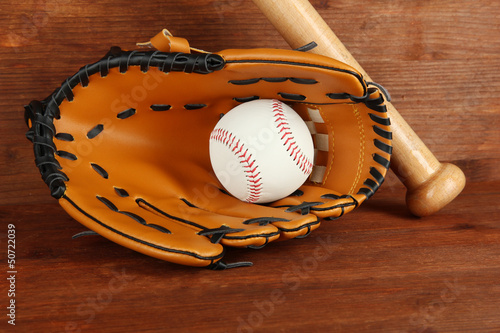 Baseball glove, bat and ball on wooden background