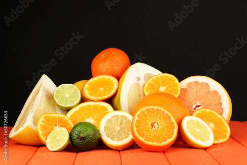 Lots ripe citrus on wooden table on black background