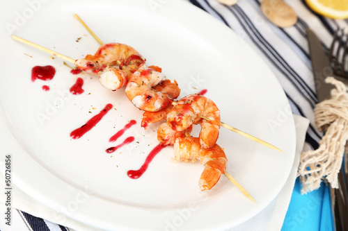 Grilled shrimp with sauce on plate on wooden table close-up