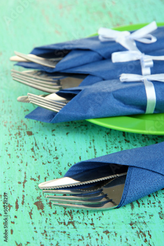 Forks and knives wrapped in blue paper napkins,