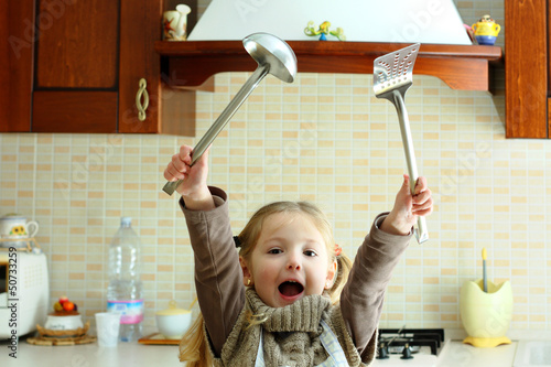 Bambina in cucina che esulta di gioia photo