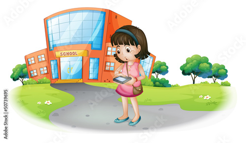 A young girl texting in front of a school building