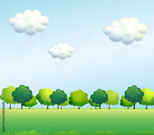 The green trees below the clear blue sky