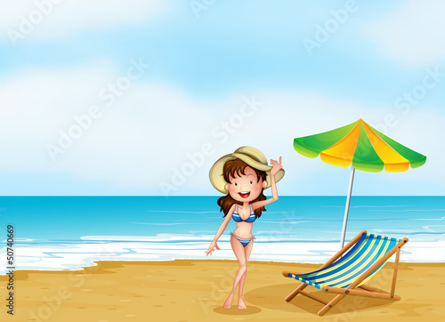A woman at the beach with an umbrella and a chair