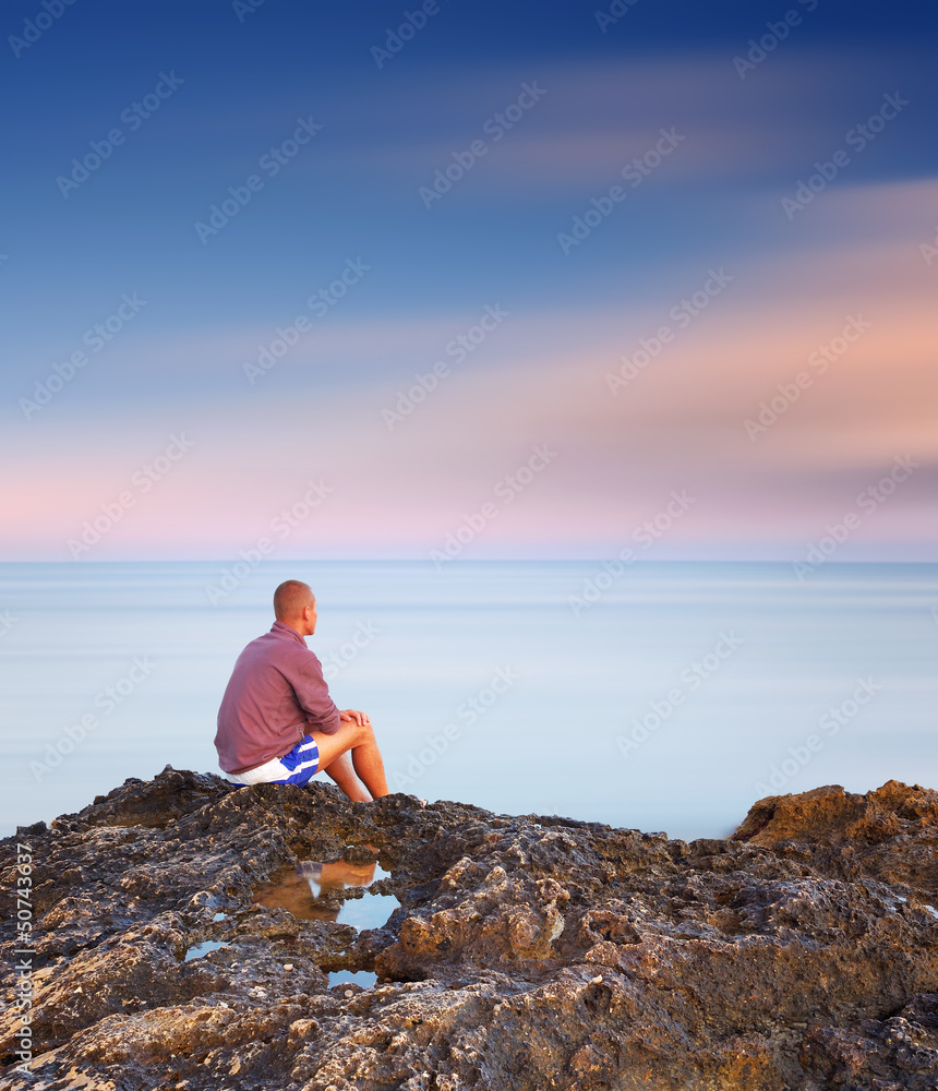 Man sitting on a rock by the sea