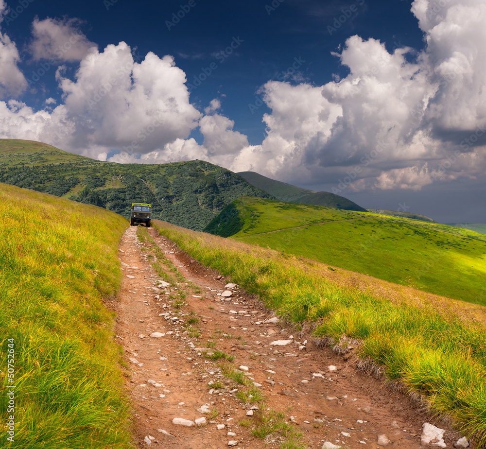 Obraz premium Offroader on the mountain road at summer