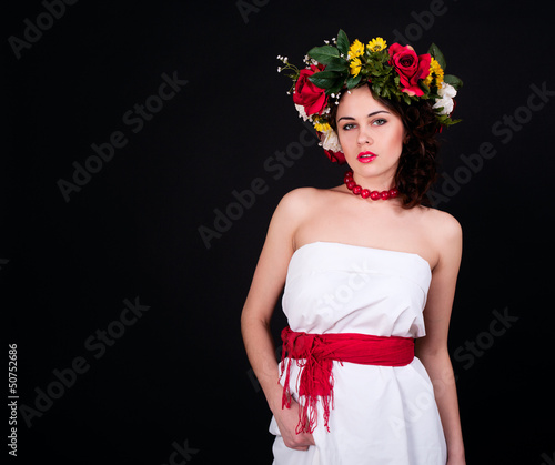 Beautiful woman in flower wreath, white dress and red sash