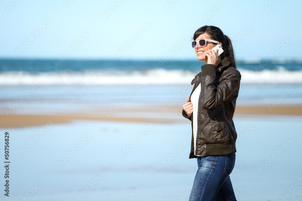 Woman with cellphone walking on beach Woman with cellphone walking on beach