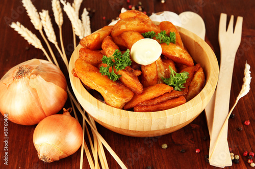 Appetizing village potatoes in bowl on wooden table close-up