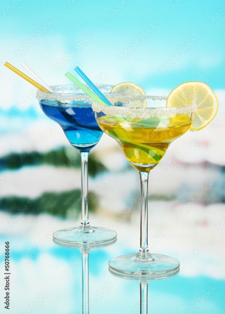 Yellow and blue cocktails in glasses on blue natural background
