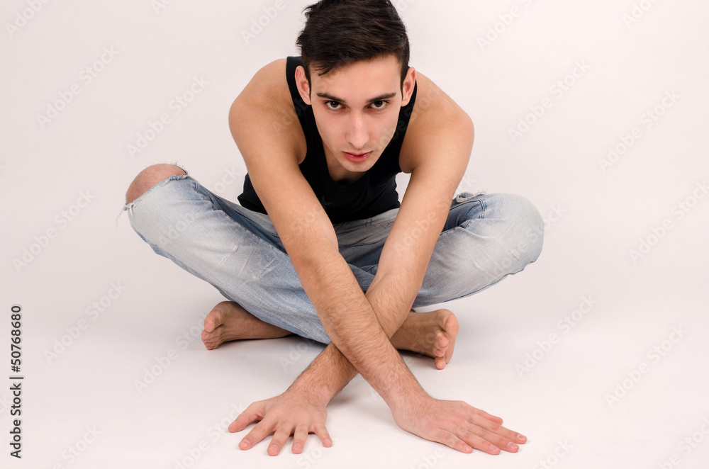 Attractive man in ripped jeans and black top stretching.