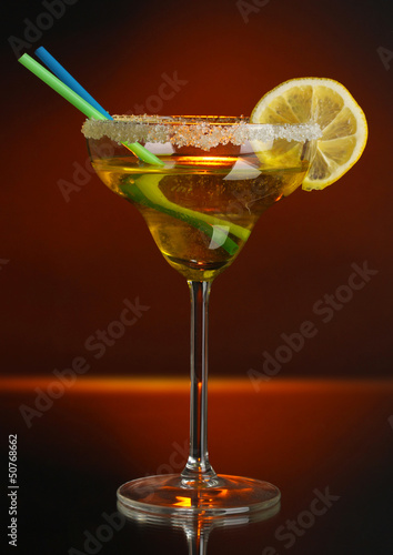 Yellow cocktail in glass on color background