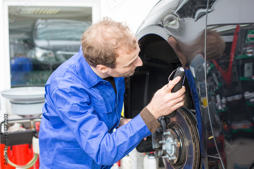 Car mechanic repairs the brakes
