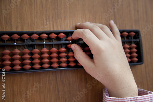 Child´s hand doing arithmetics with a Japanese abacus
