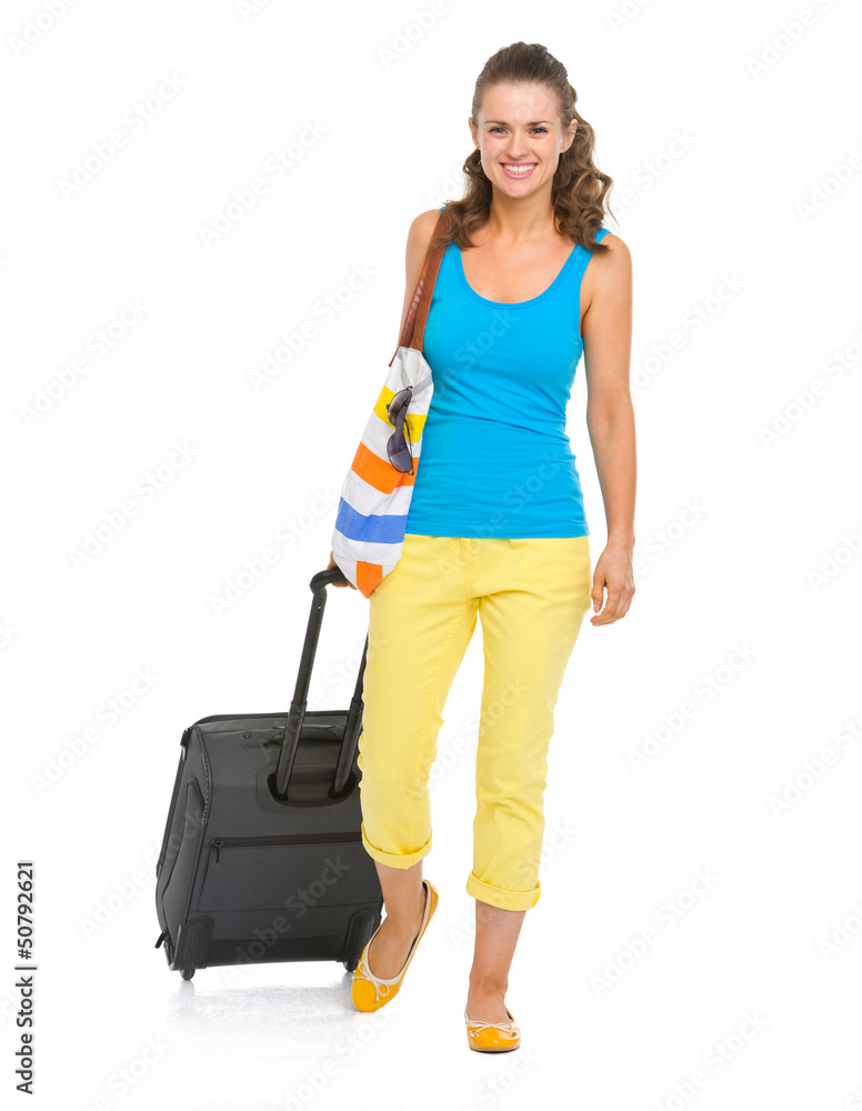 Smiling young tourist woman with wheel bag going straight Smiling young tourist woman with wheel bag going straight