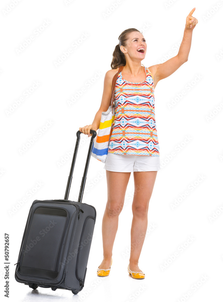 Smiling tourist woman with wheel bag pointing on copy space Smiling tourist woman with wheel bag pointing on copy space