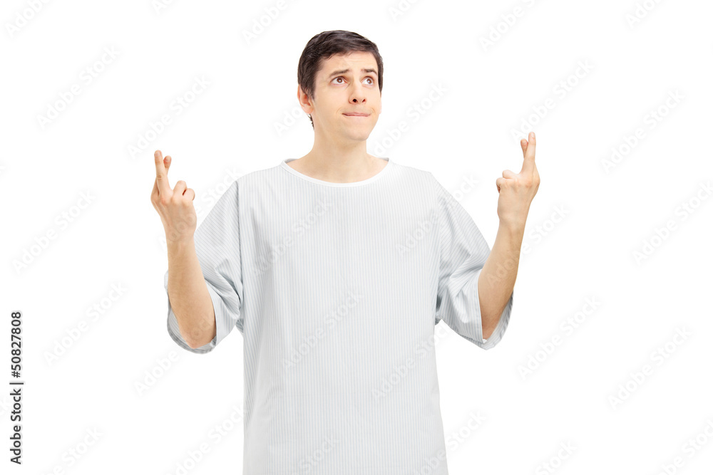 Male patient in a hospital gown with fingers crossed posing Male patient in a hospital gown with fingers crossed posing