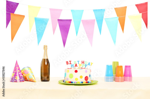 Bottle of sparkling wine, plastic glasses, party hats and birthd