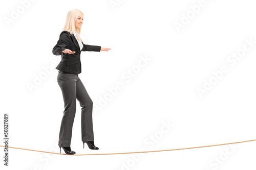 Full length portrait of a young woman walking on a rope