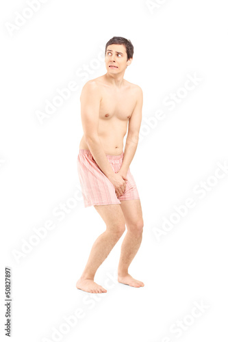 Full length portrait of an embarrassed naked man in underwear