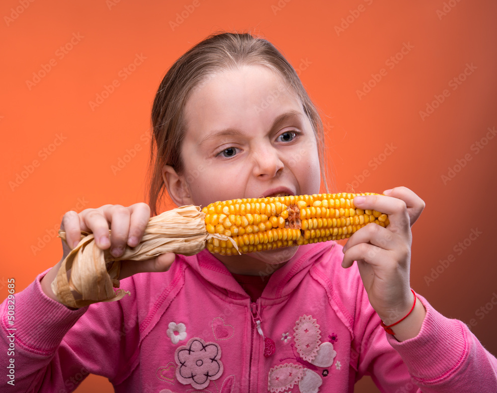 Funny girl truing to bite dry corn Funny girl truing to bite dry corn