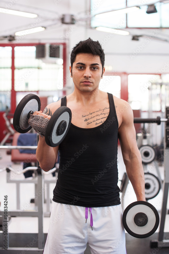 Young man exercising with dumbbells in a gym. Young man exercising with dumbbells in a gym.
