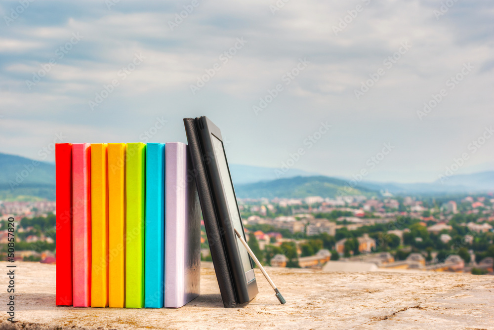 Stack of colorful books with e-book reader