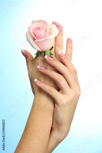 Beautiful woman hands with rose, on blue background