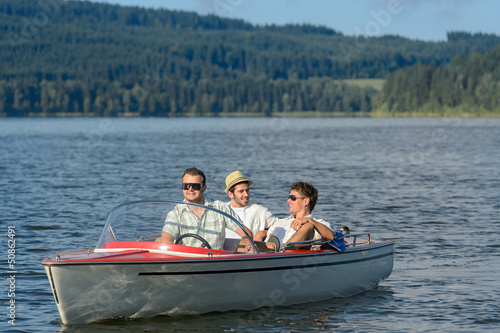 Young men sitting in motorboat scenic landscape © CandyBox Images