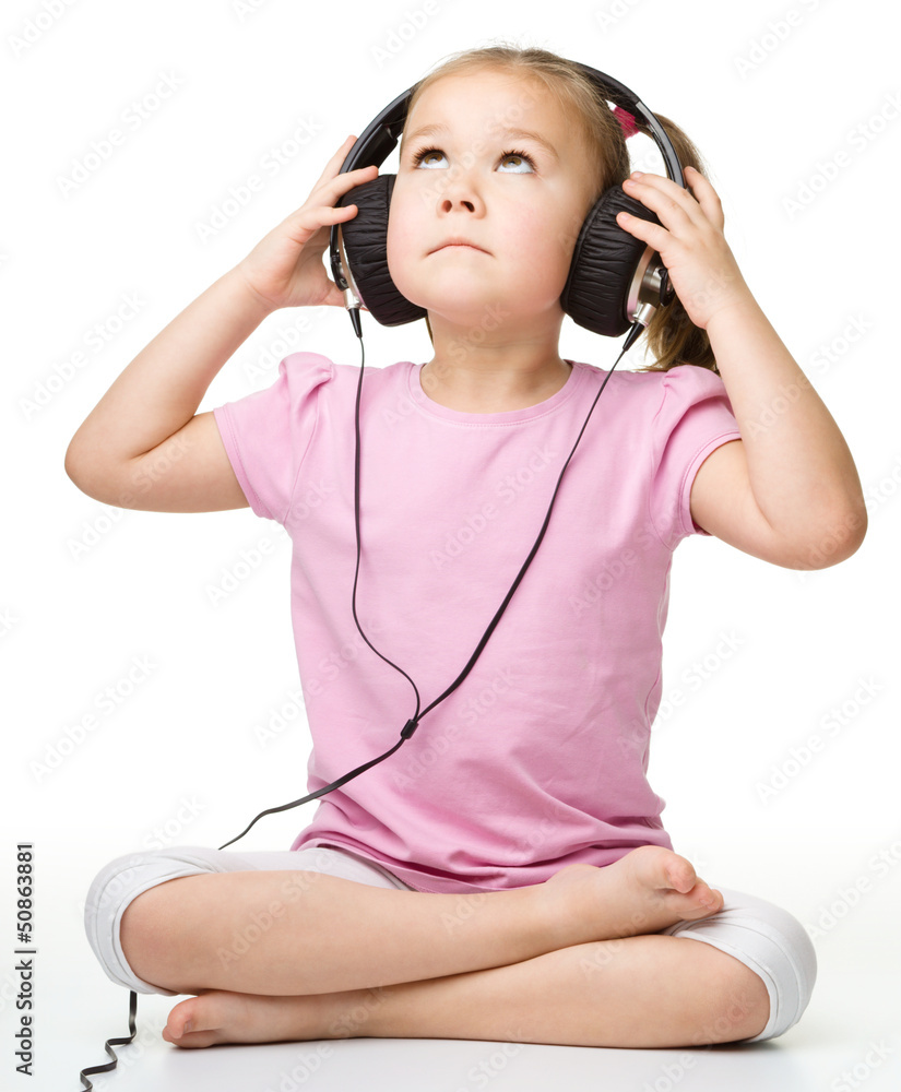 Cute little girl enjoying music using headphones Cute little girl enjoying music using headphones