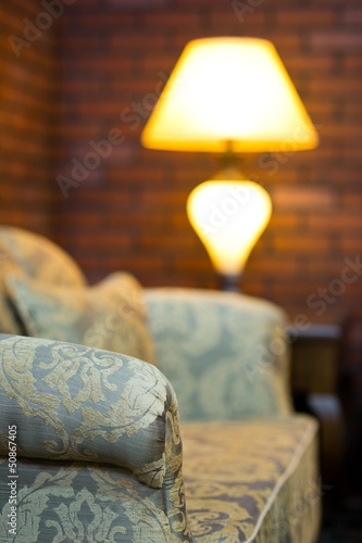 Old sofa in a room with lamp and red brick wall decor
