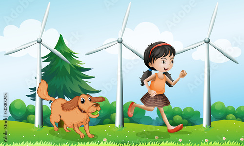 A girl playing with her dog near the windmills