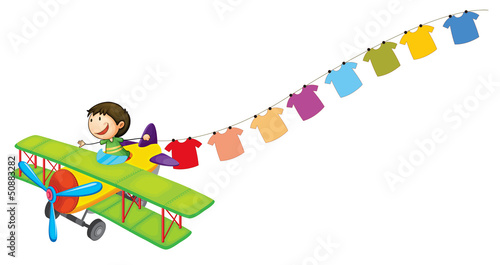 A boy in a plane with hanging clothes