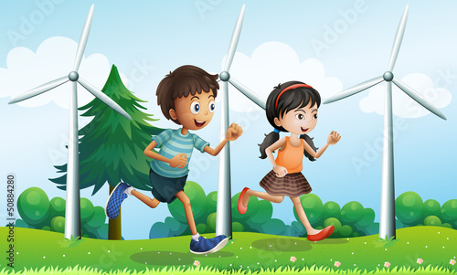 A girl and a boy running in the hill with windmills