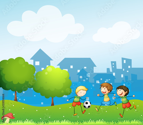 Three kids playing soccer in the hill