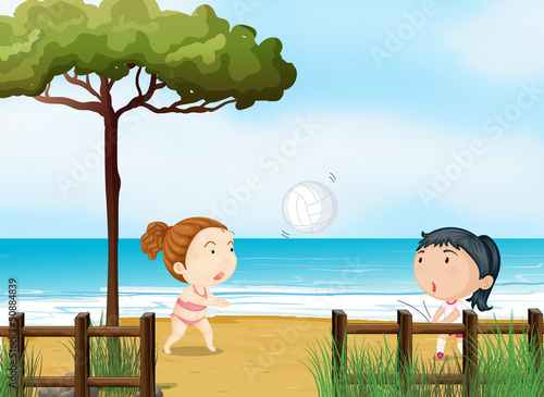 Two little girls playing volleyball at the beach