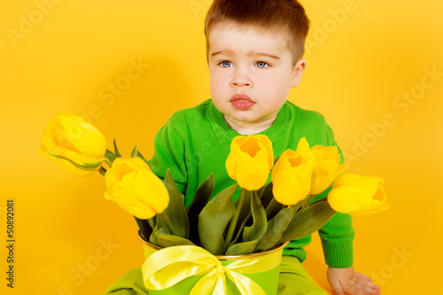 Little baby boy with bouquet of yellow tulips