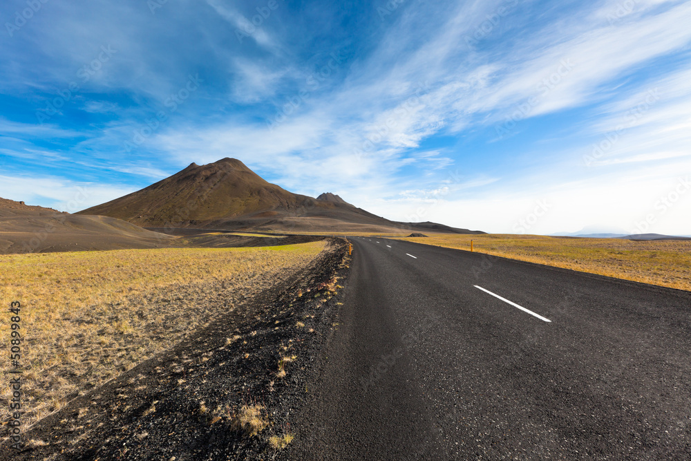 Highway through gravel lava field landscape under a blue summer