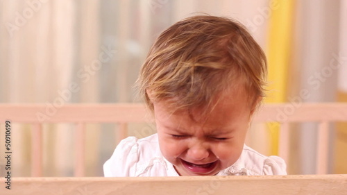 Small girl crying and standing in her bed