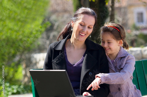 mother and daughter in the park with laptop