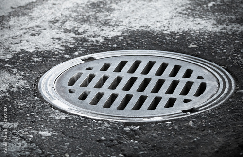 Sewer manhole on the urban asphalt road. Closeup photo