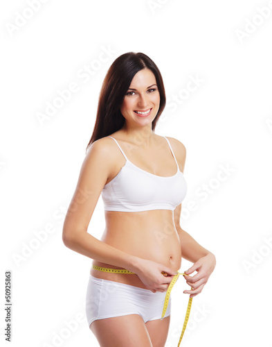 Young surprised pregnant woman measures her waist with a tape