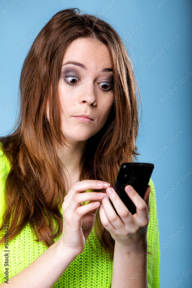 Woman texting while looking surprised on phone Woman texting while looking surprised on phone