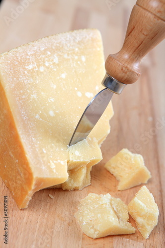 Parmesan cheese with knife on wooden table