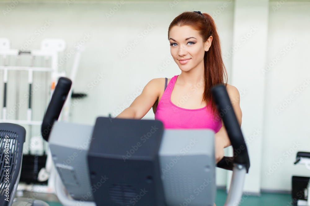 fitness model exercising on a cardio machine in fitness center fitness model exercising on a cardio machine in fitness center