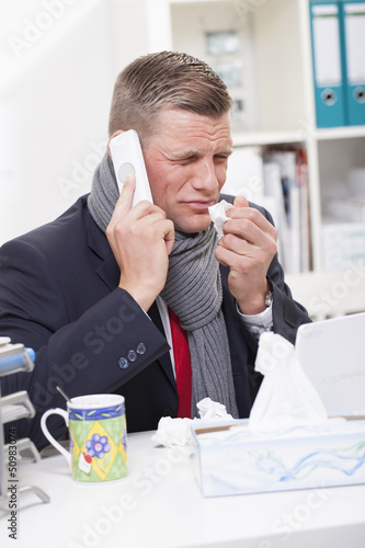Mann mit Erkältung im Büro