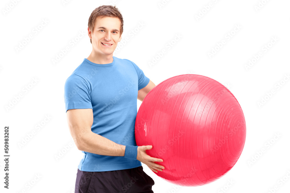 A young male athlete holding a pilates ball A young male athlete holding a pilates ball