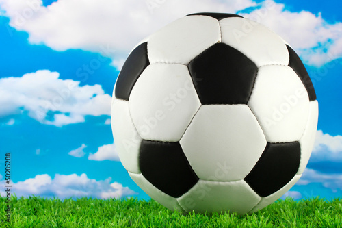 football ball on green grass, on blue sky background